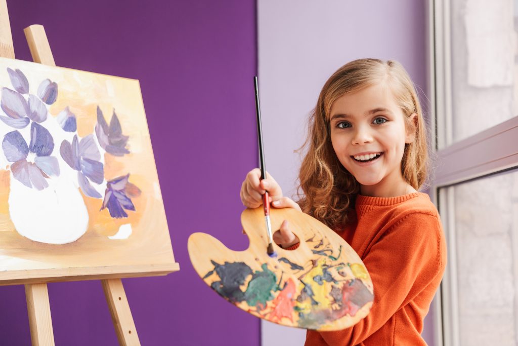 child painting a picture of a purple flower