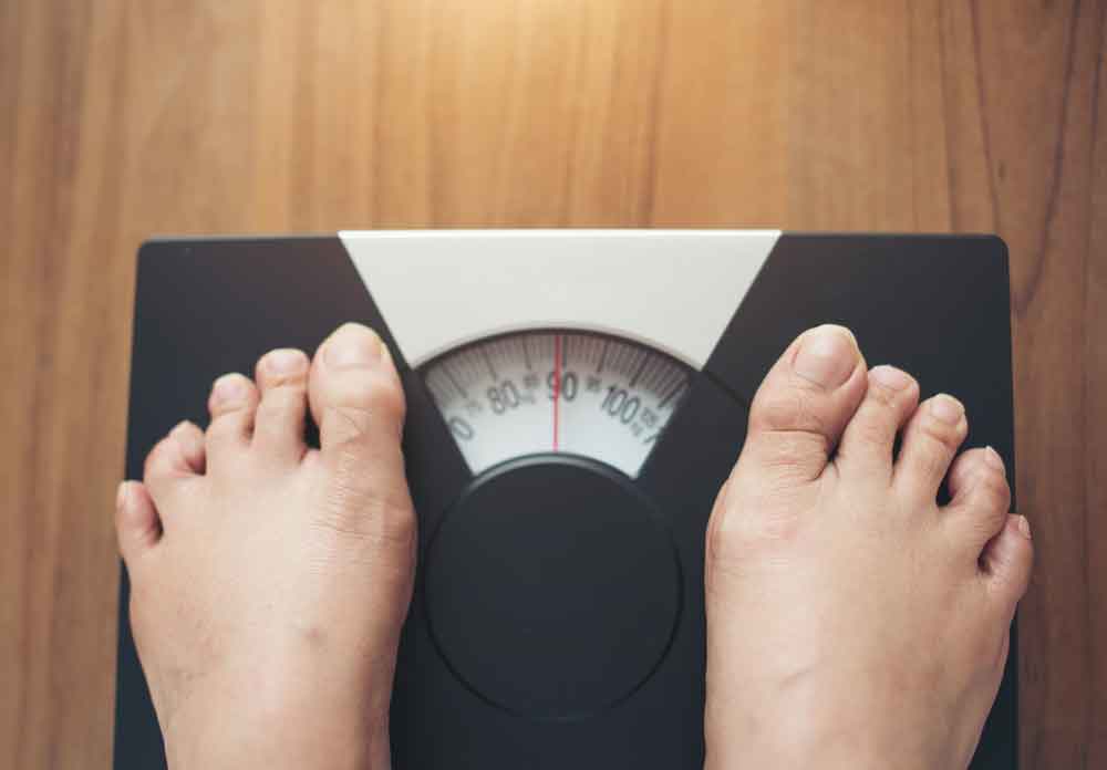 person checking their weight on a weighing scale