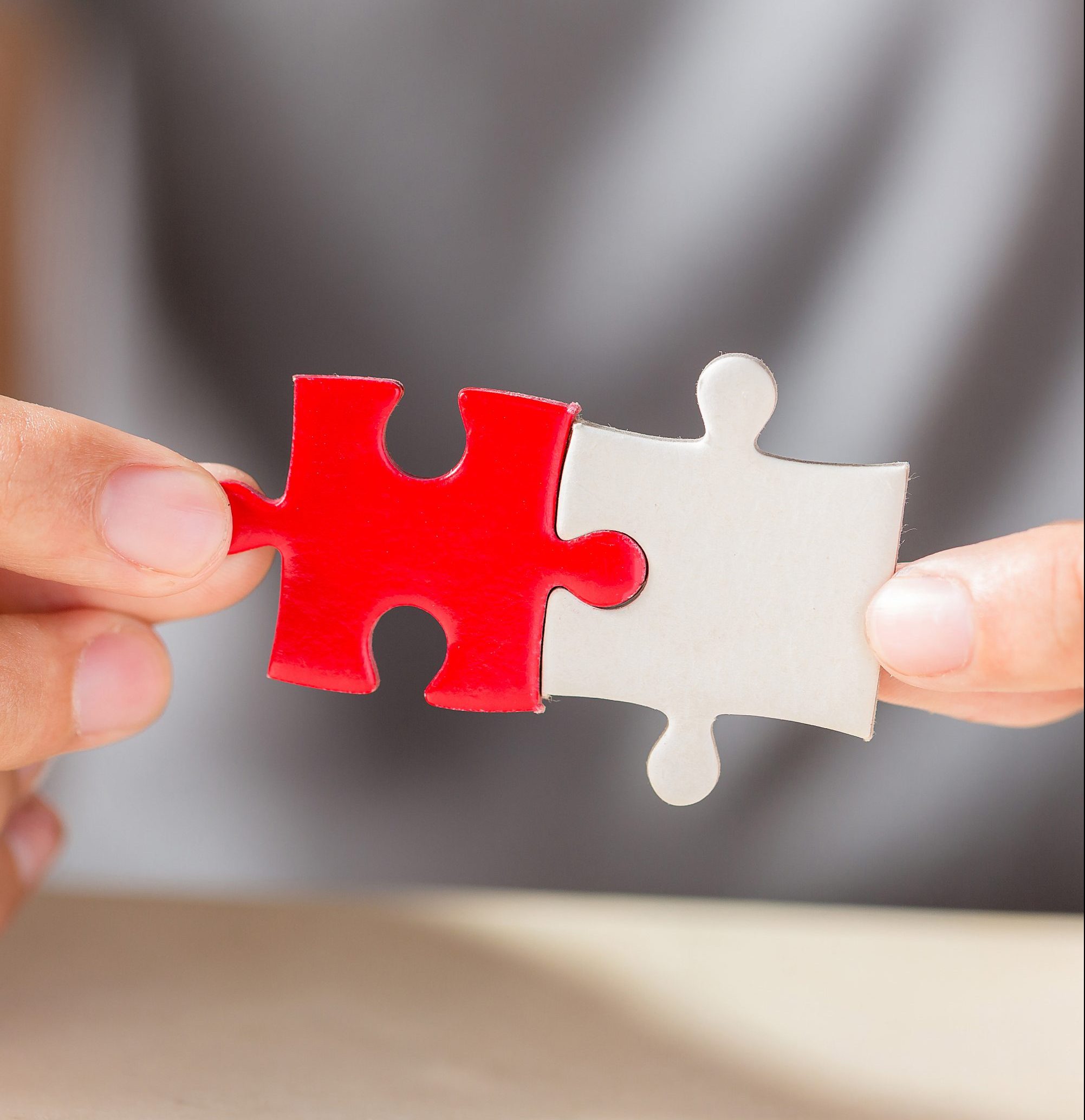 hand connecting two puzzle pieces on table background